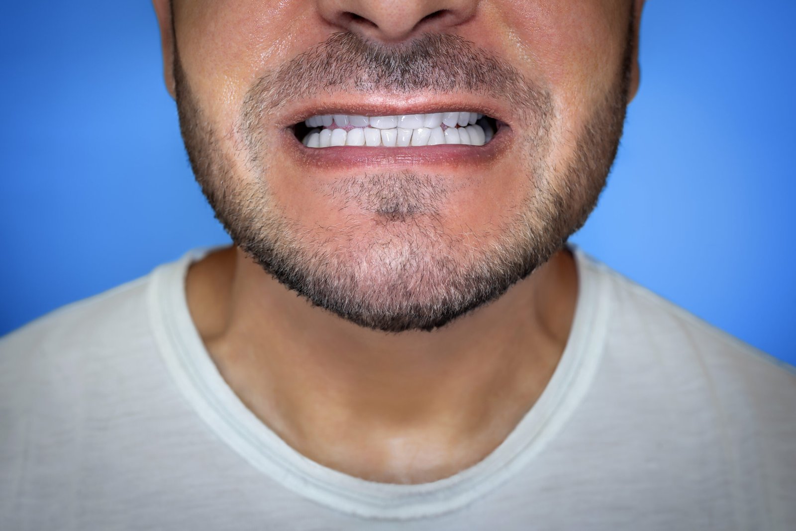 A man after teeth whitening on colored background, close-up.